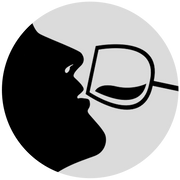 The silhouette of a person drinking from a wine glass.